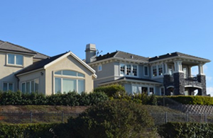 雲一つない青空の下に家が二軒並んでいます。左側は白い壁の２階建ての家。右側はテラスのある２階建ての洋館。二軒は小高い丘の上に建っています。